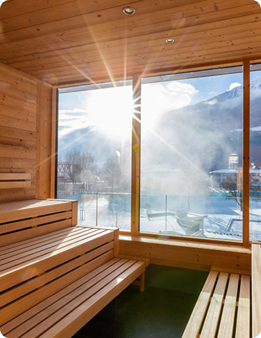Holzsauna mit großem Fenster und Blick auf die Berge
