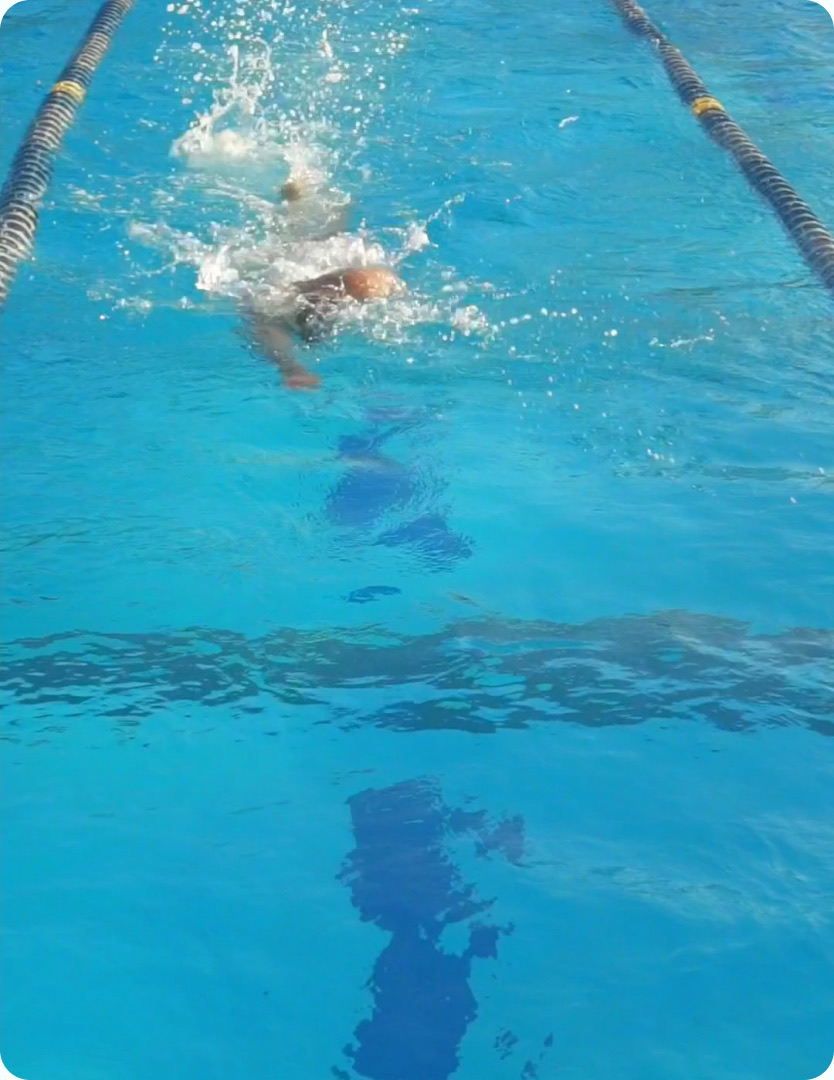 Schwimmer krault im türkisblauen Sportbecken