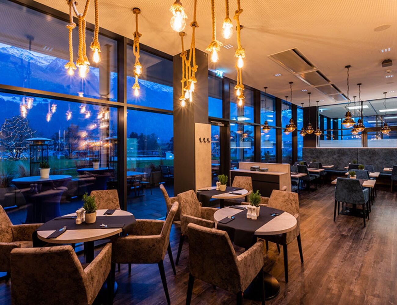 Stimmungsvoll beleuchteter Gastraum des Restaurants Surfers mit Blick auf die Berge